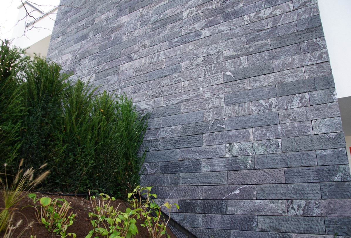 Dunkle Naturstein Mauerverblender als Verkleidung einer Hauswand